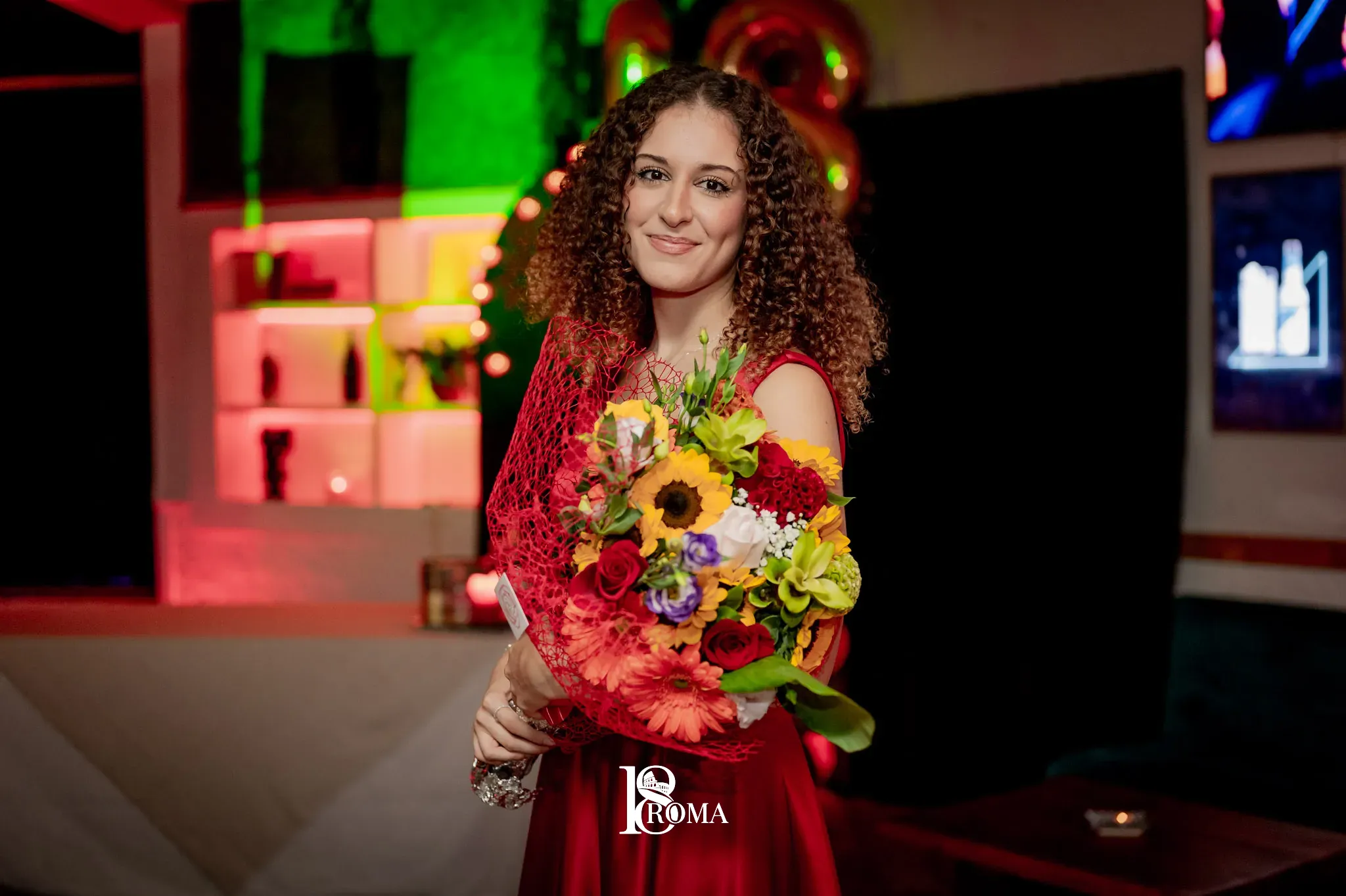 Ragazza sorridente con un mazzo di girasoli e fiori colorati durante una festa serale