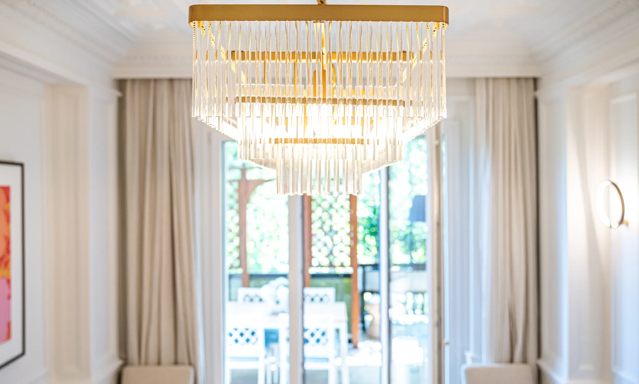 Ambiente bianco con lampadario di cristallo davanti alla portafinestra